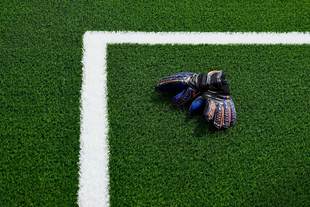Goalkeeper gloves on green artificial turf field